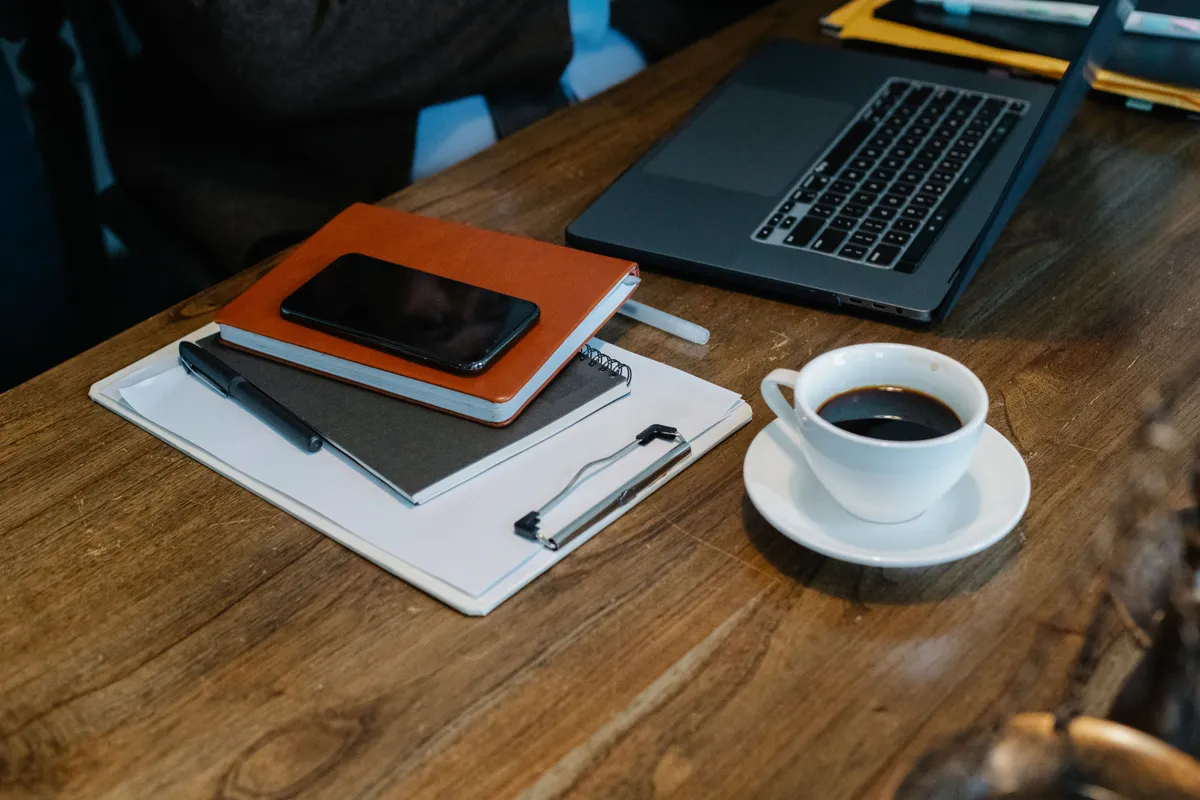 Bureau avec ordinateur portable, carnets, téléphone et café
